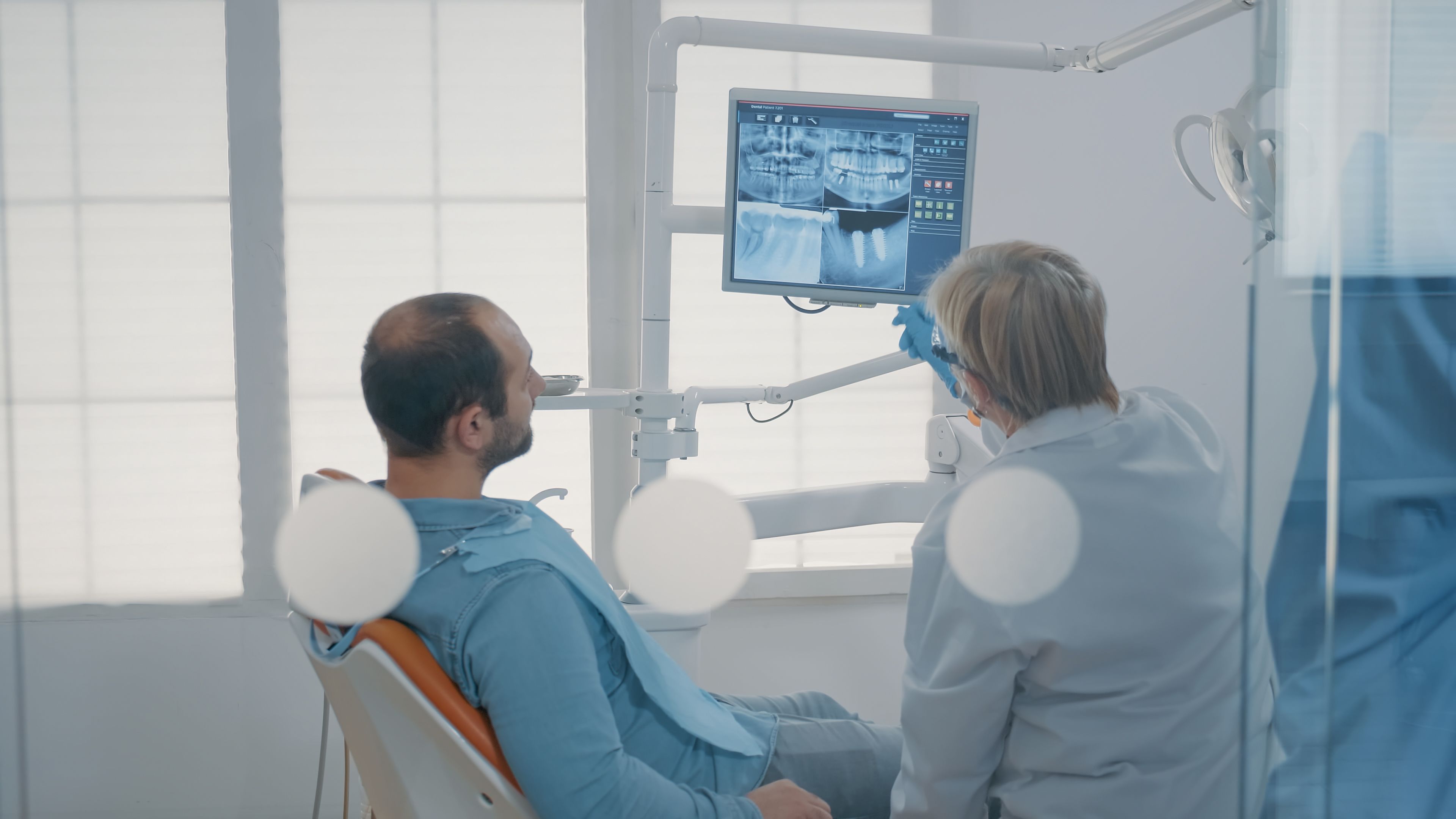 mature-dentist-pointing-teeth-radiography-monitor-explain-dentititon-diagnosis-patient-with-toothache-dental-expert-showing-x-ray-scan-results-man-with-cavity-pain